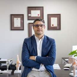 Dr. Hans Jacobs in a professional setting with anatomical models, showcasing expertise in orthopedics and patient care.